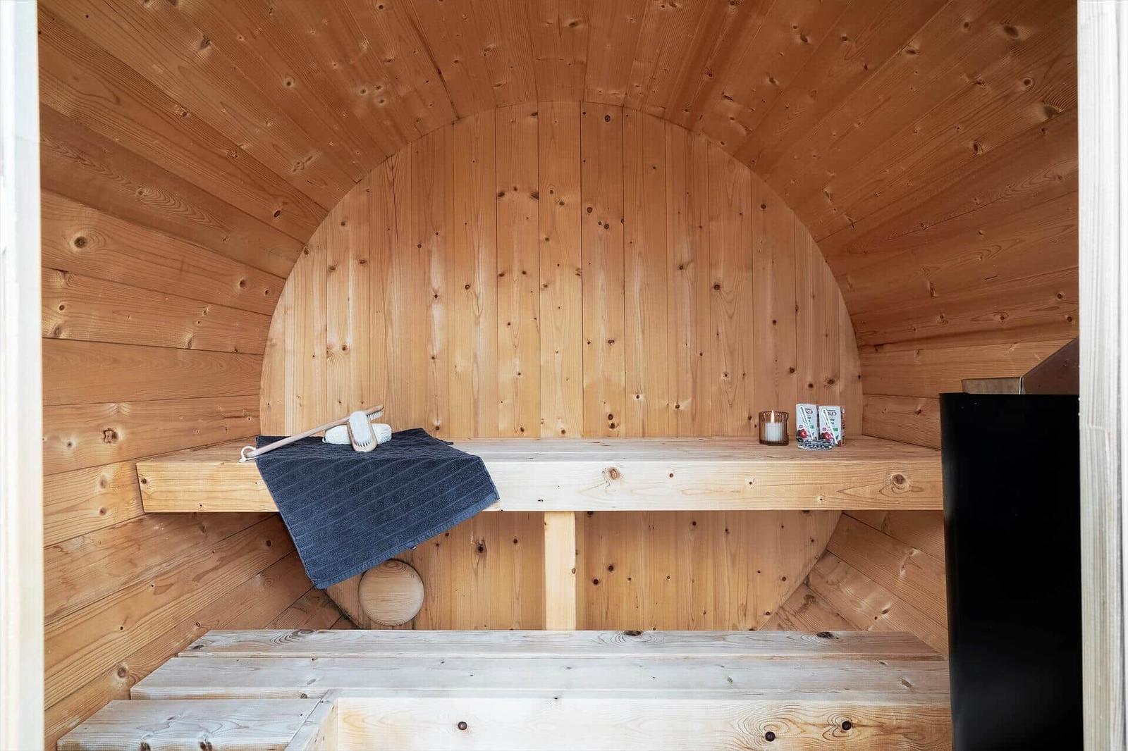 Holzsauna mit Sitzbank, Handtuch und Saunakissen.
