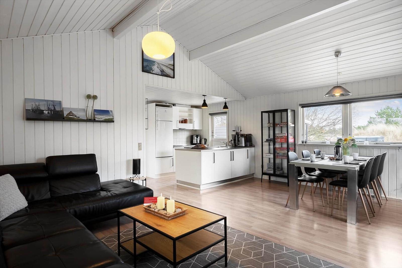 Wohnzimmer mit Sofa, Esstisch und Küche unter weißem Holzdecken