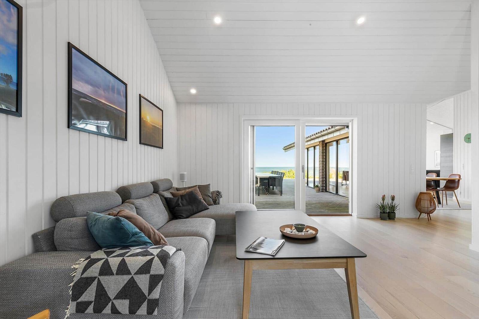 Wohnzimmer mit Sofa, Couchtisch und Blick auf den Strand