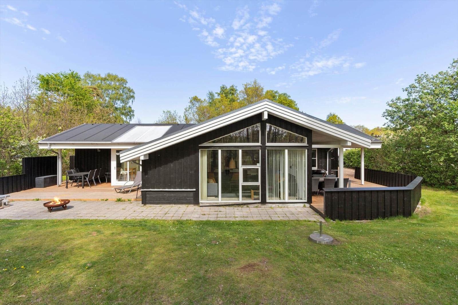 Moderne Holzhütte mit großem Garten und Terrasse. Sicht auf Wohn- und Essbereich.