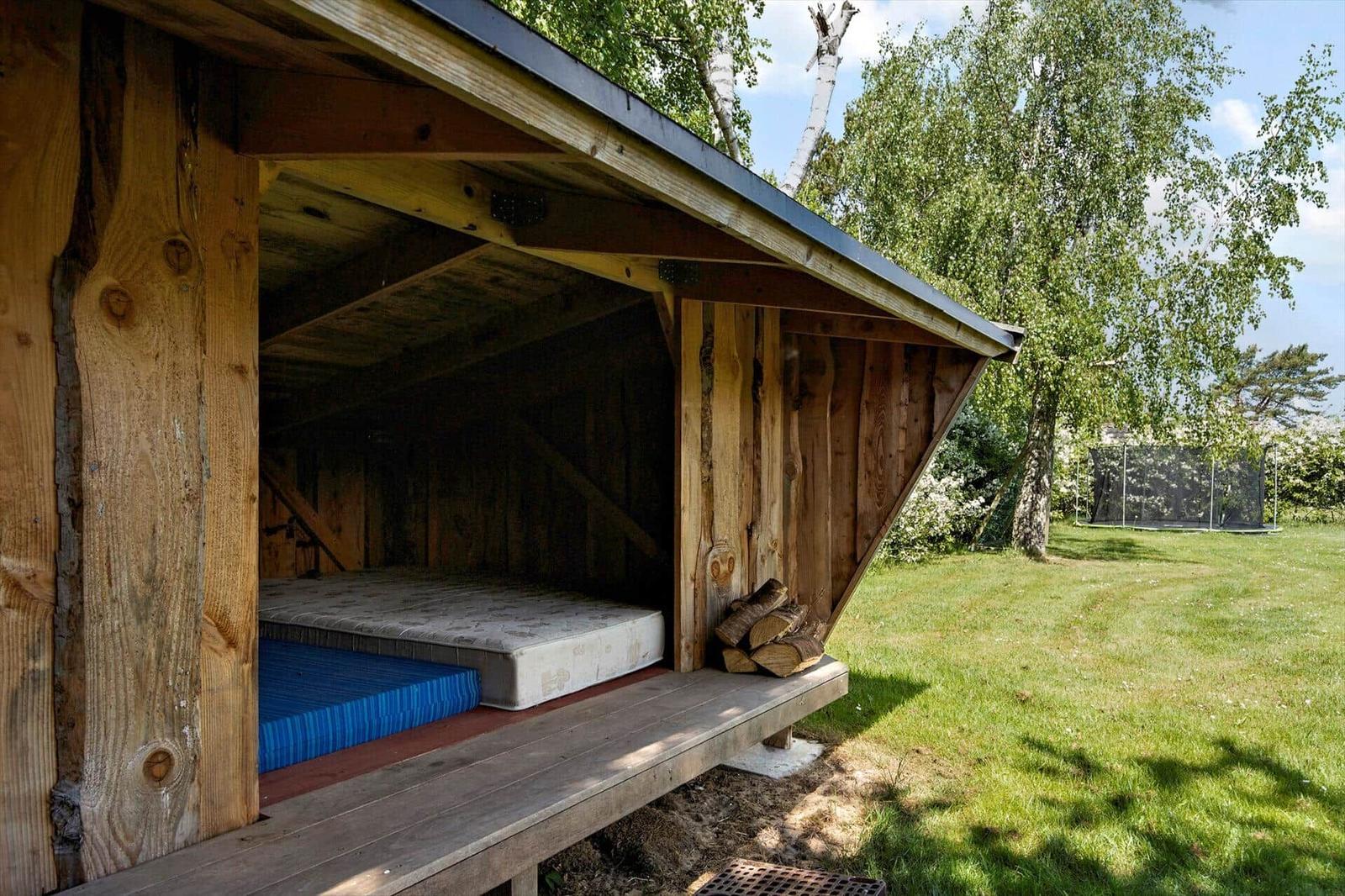 Holzkonstruktion mit Matratze und Schlafplatz im Freien.