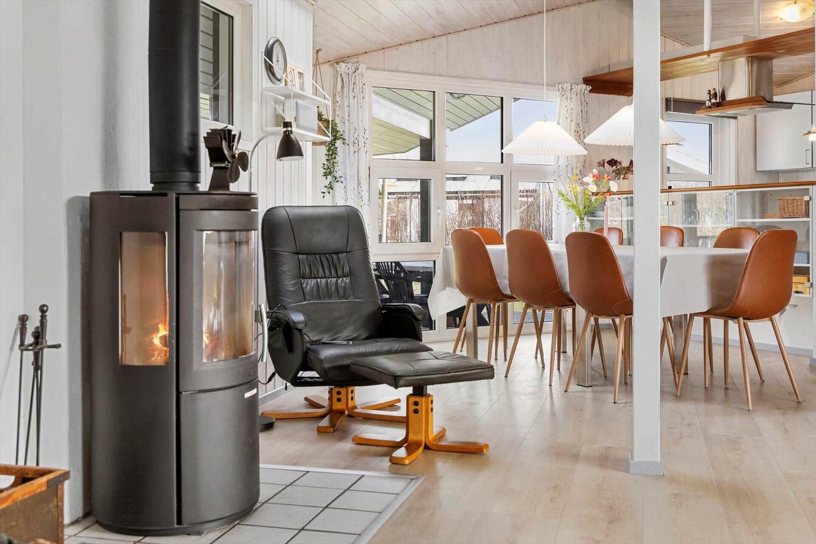 Raum mit Kamin, Ledersessel und Esstisch mit braunen Stühlen.