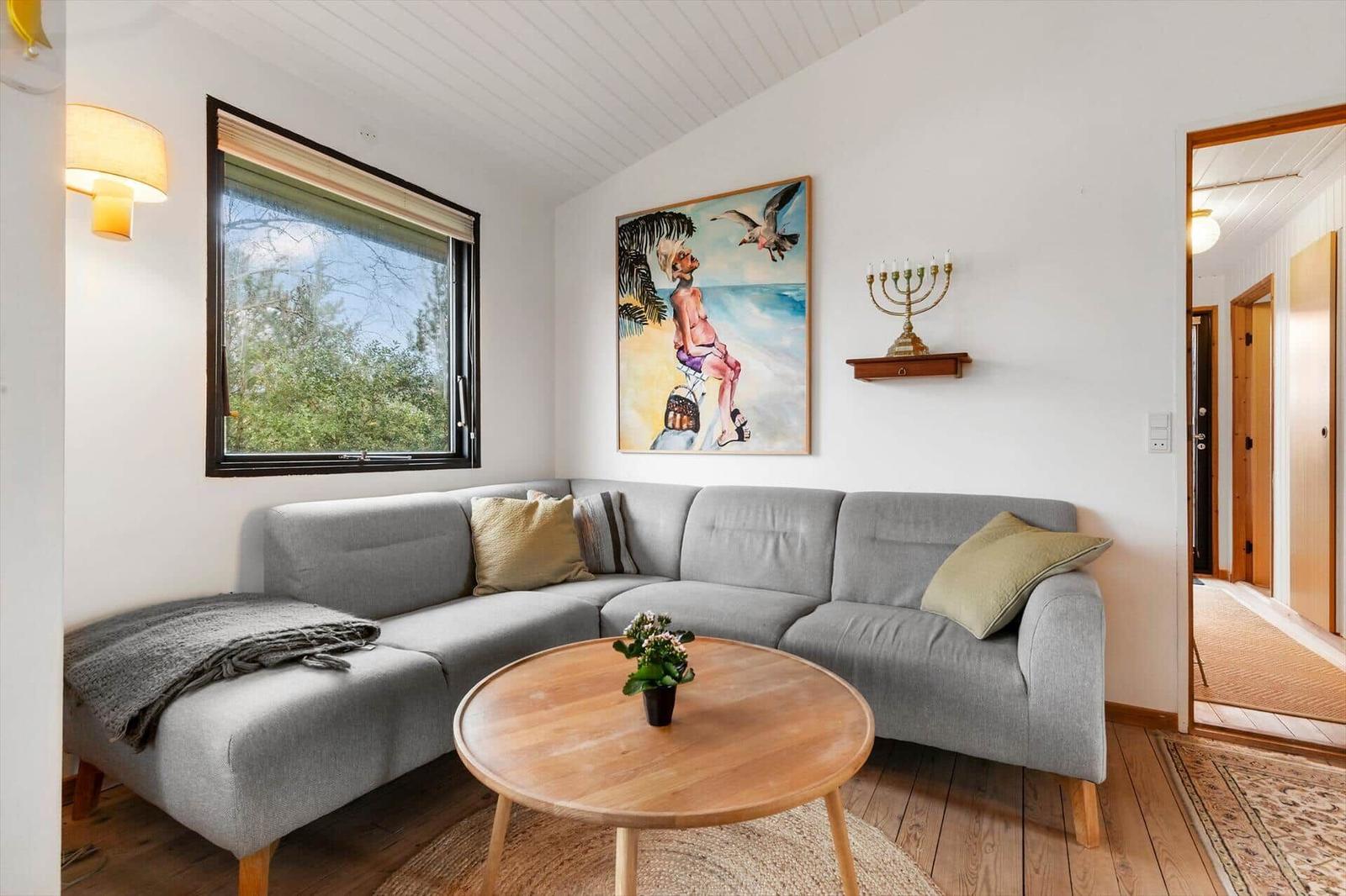 Ein Wohnzimmer mit grauem Sofa, runden Tisch und Wandbild.