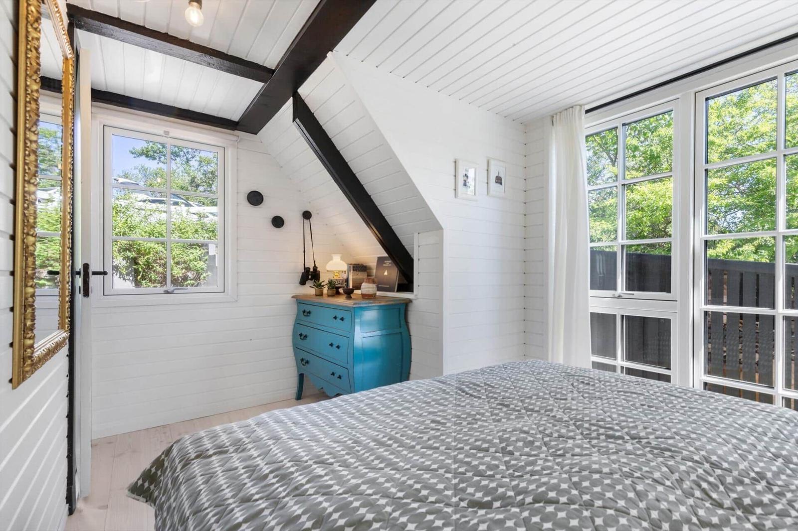 Schlafzimmer mit Dachschräge, blauem Schrank und großem Fenster.