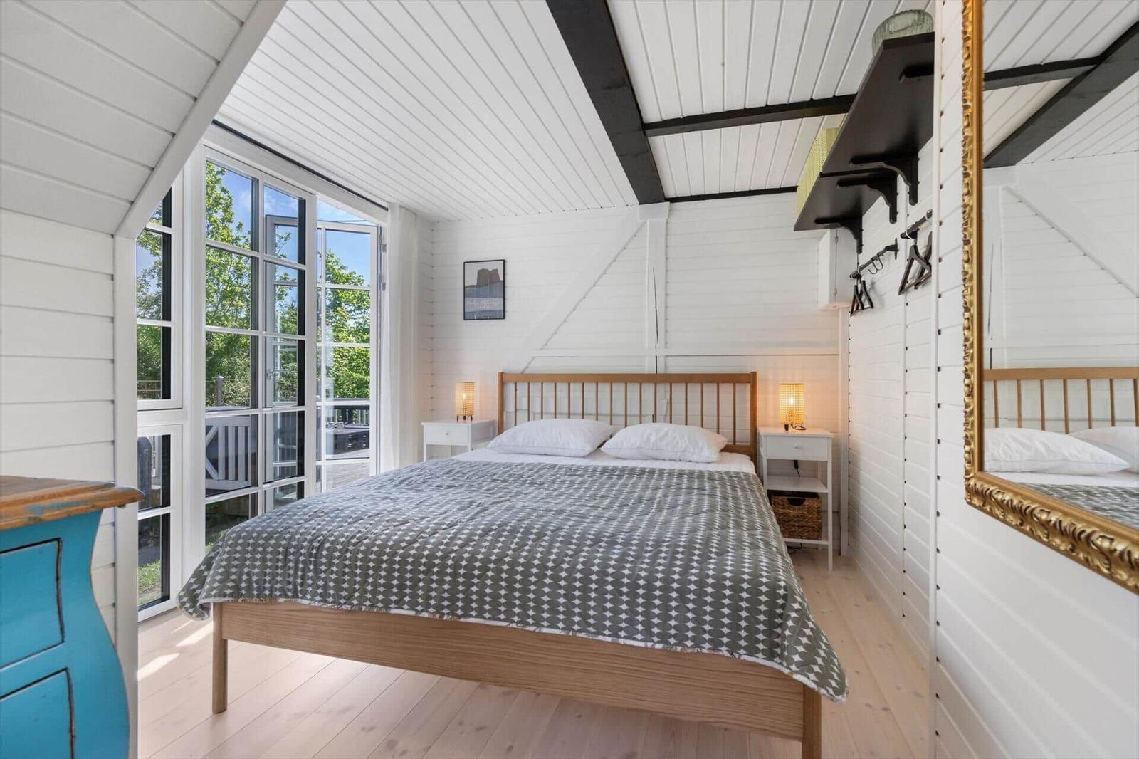 Schlafzimmer mit Bett, Fenster und Spiegel an der Wand.