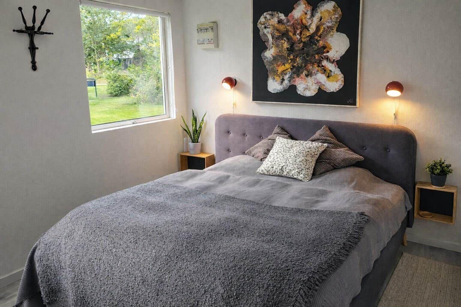 Schlafzimmer mit Bett, Fenster und Wandbild.