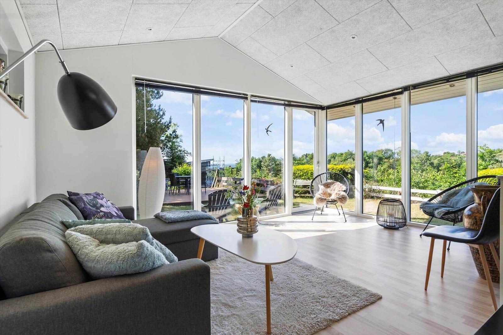 Wohnzimmer mit großem Fensterblick auf Garten und Himmel