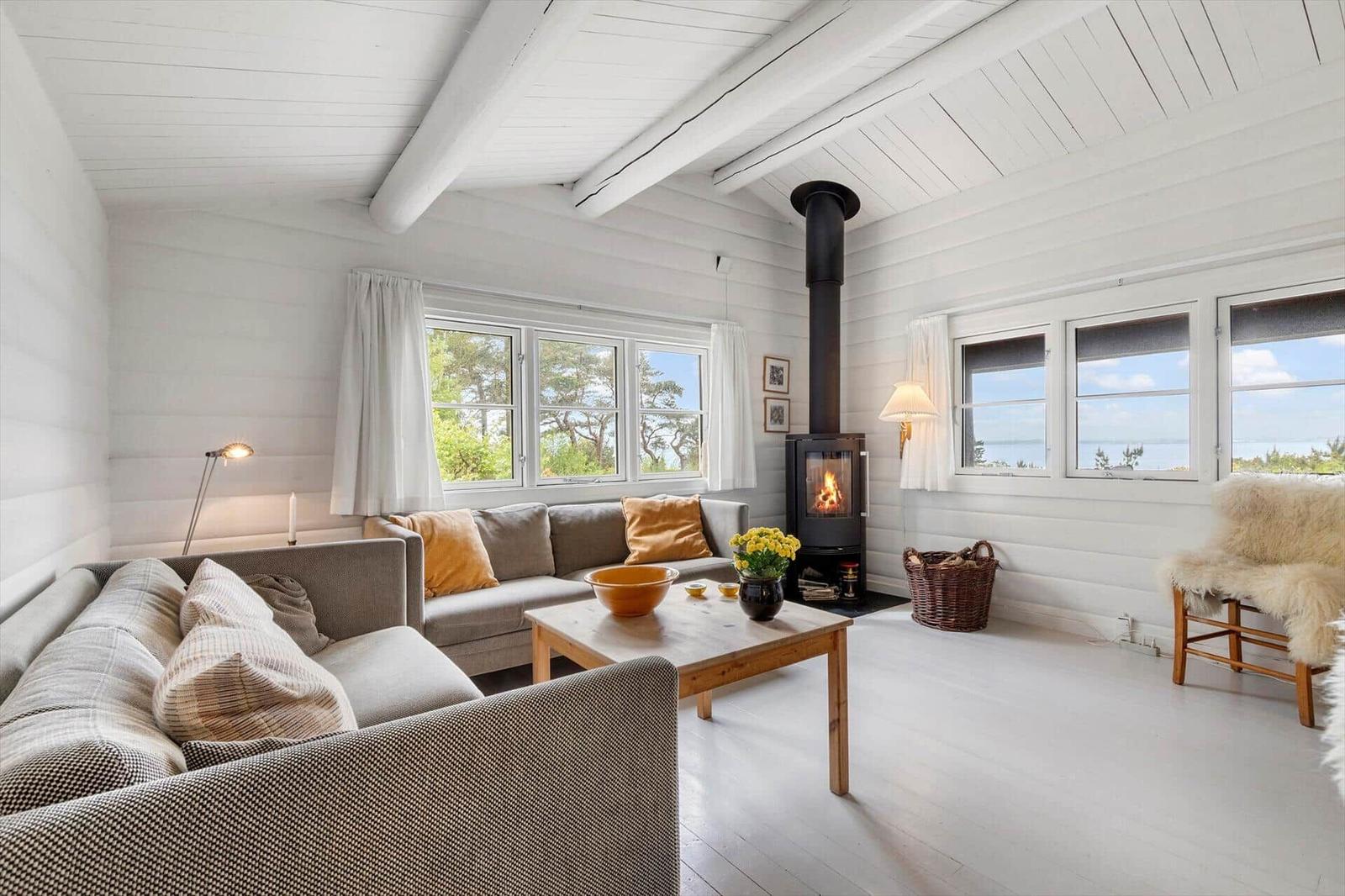 Wohnzimmer mit Sofa, Kamin und Fenstern zum Meer