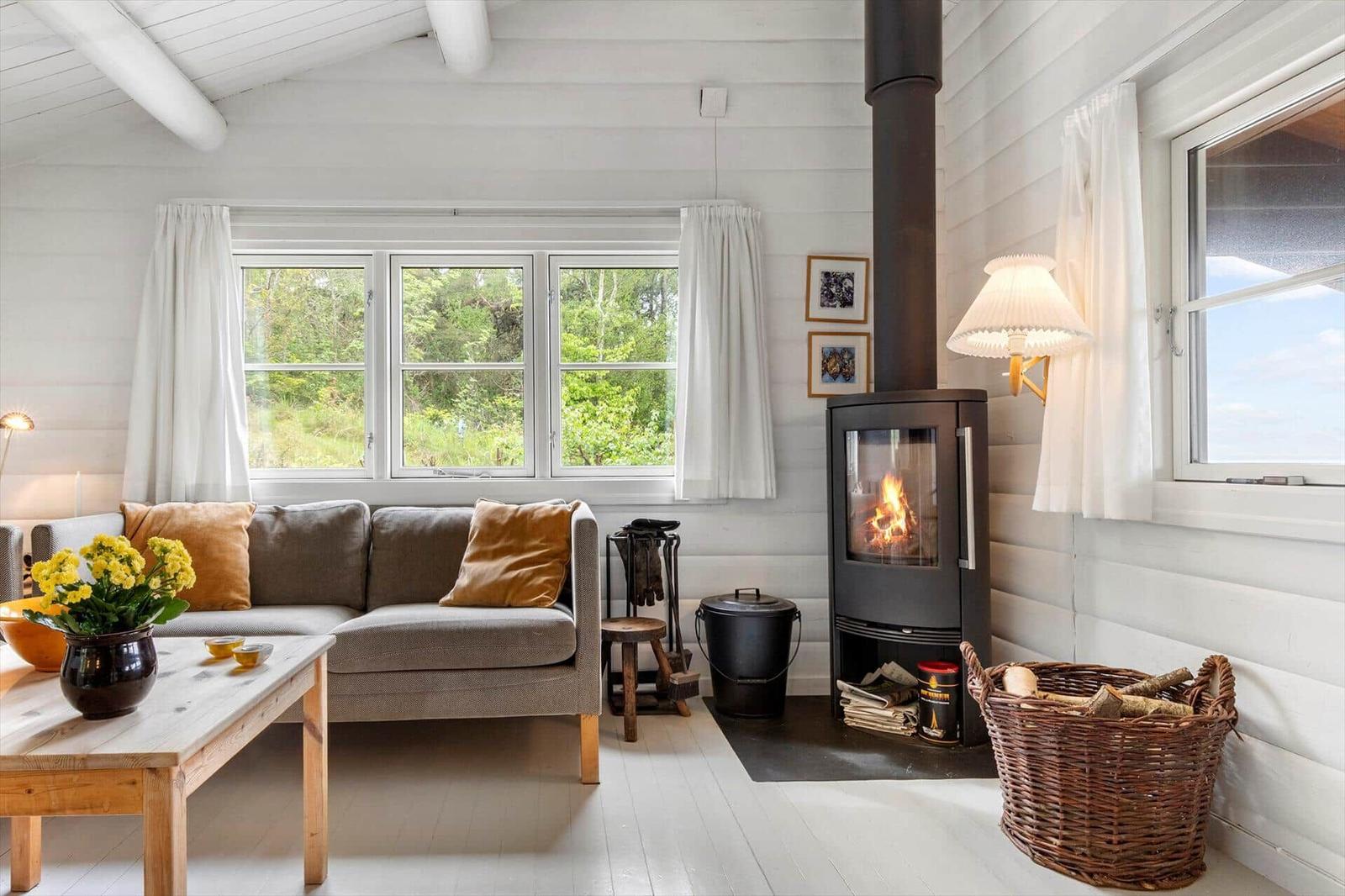 Ein Wohnzimmer mit Sofa, Kamin und Fenstern zum Blick auf die Natur.