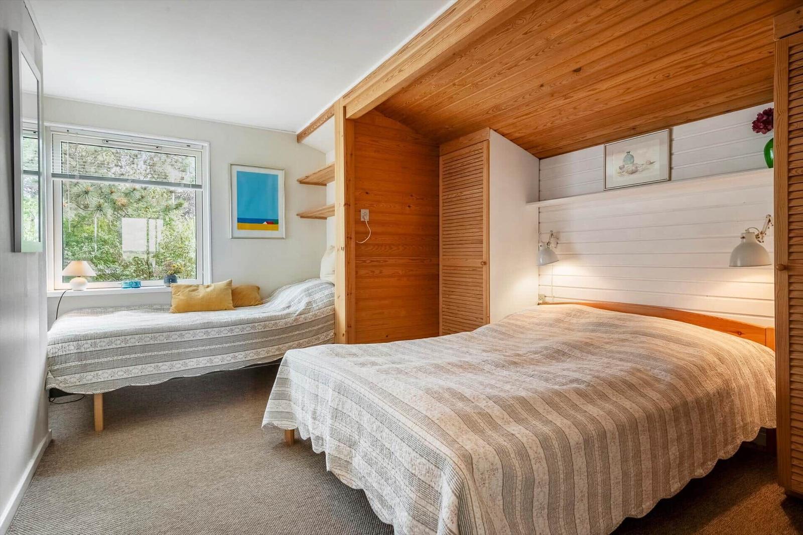 Zimmer mit zwei Betten, Holzdecke und Fenster mit Blick auf Grün.