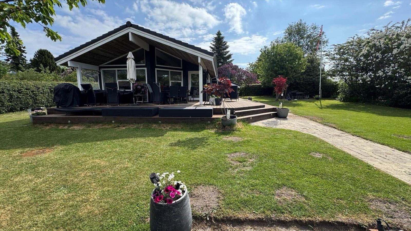 Moderne Villa mit Terrasse, Garten und Grillplatz. Blick auf das Haus mit Pflanzen.