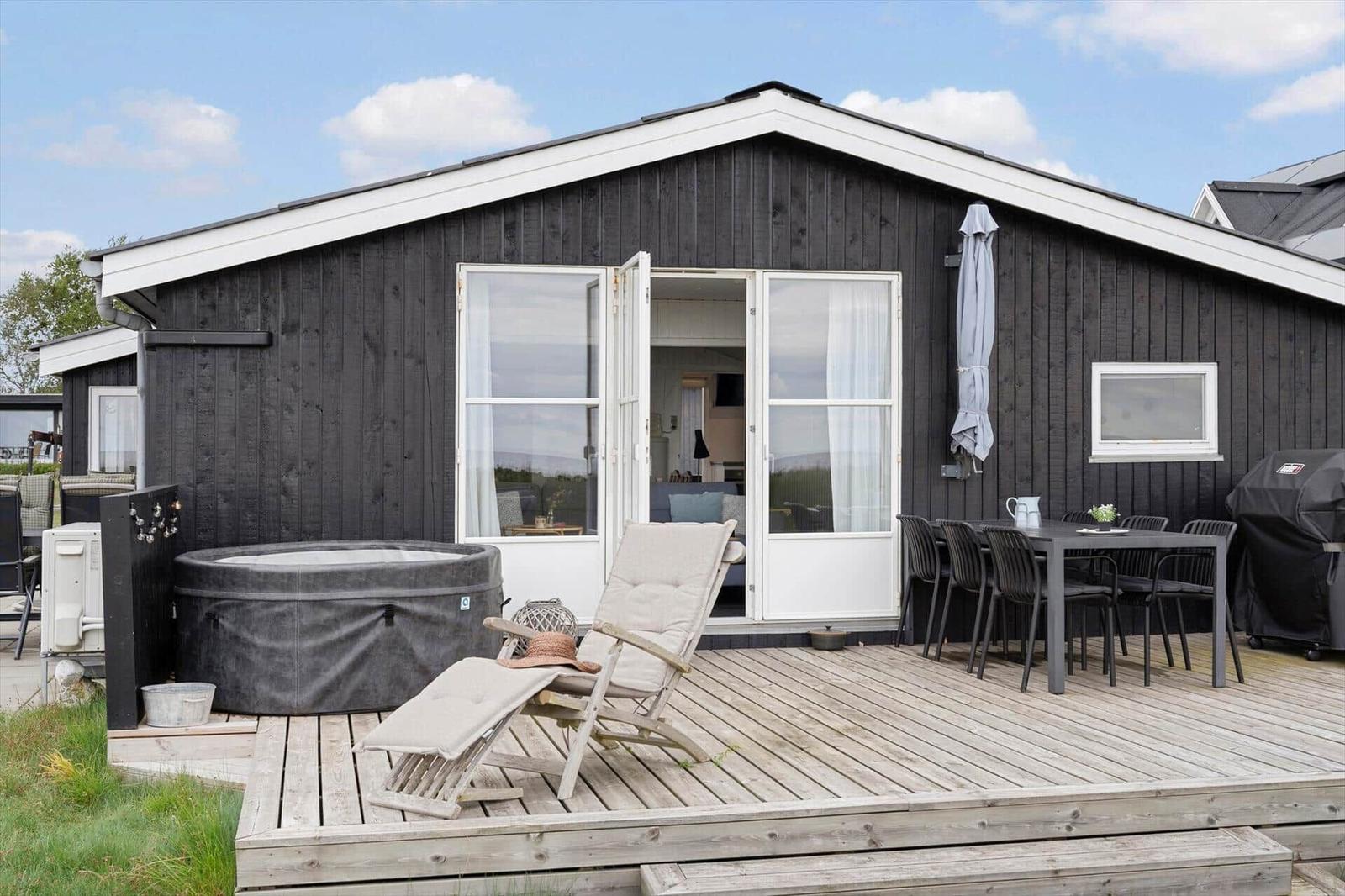 Haus mit Terrasse, Whirlpool und Sitzgelegenheiten.