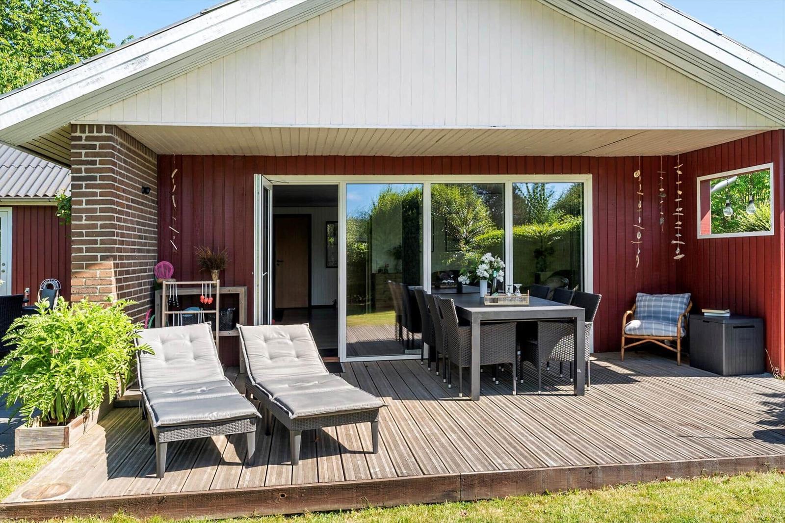 Terrasse mit Liegestühlen, Esstisch und Blick in die Wohnung.