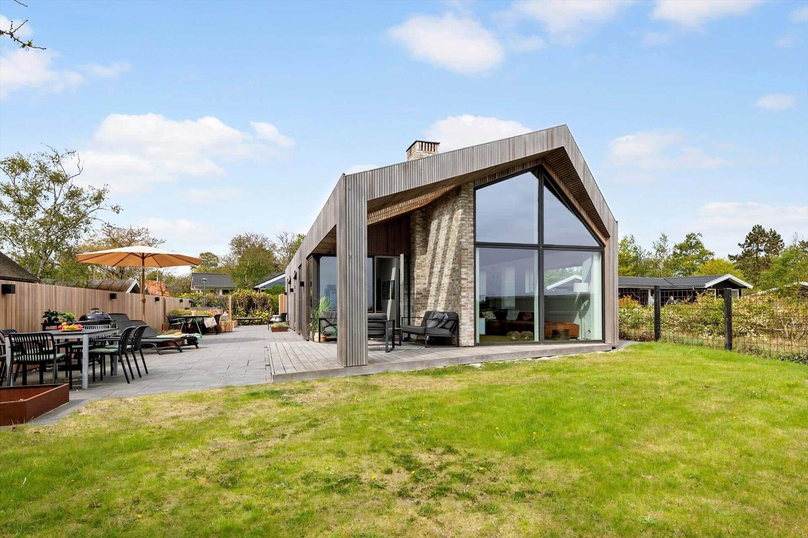 Moderne Villa mit großem Garten und Terrasse mit Sitzgelegenheiten.