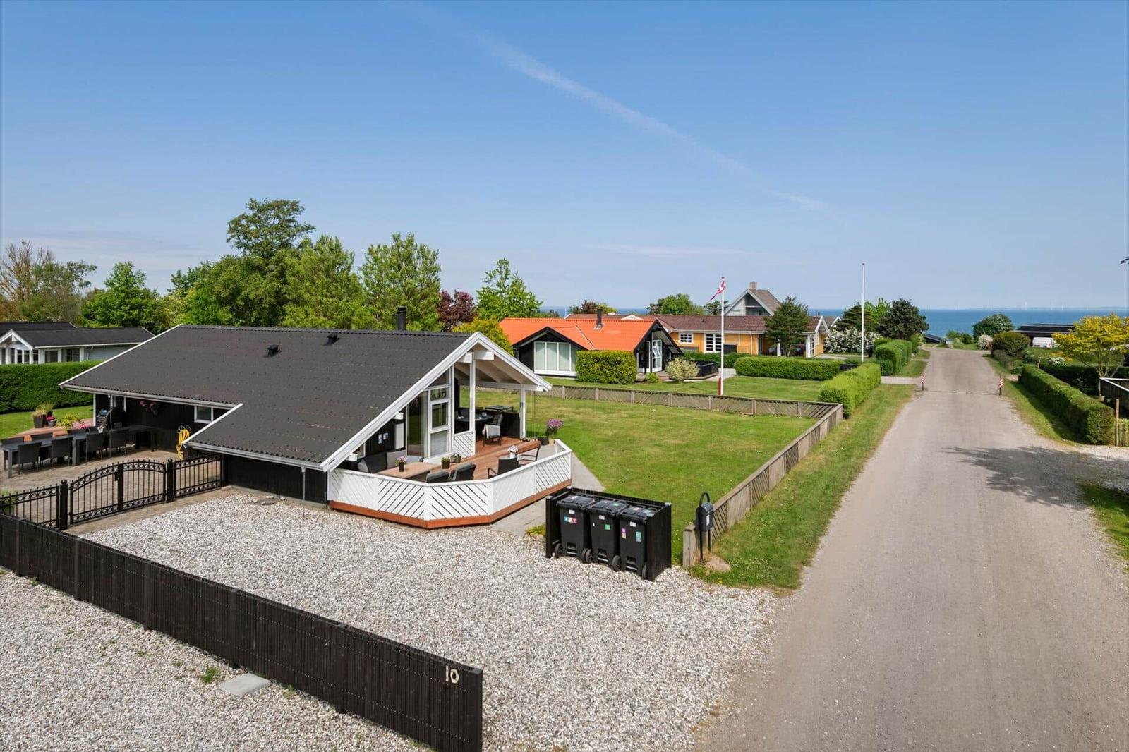 Haus mit Terrasse und Garten, Blick auf Meer und Straße.