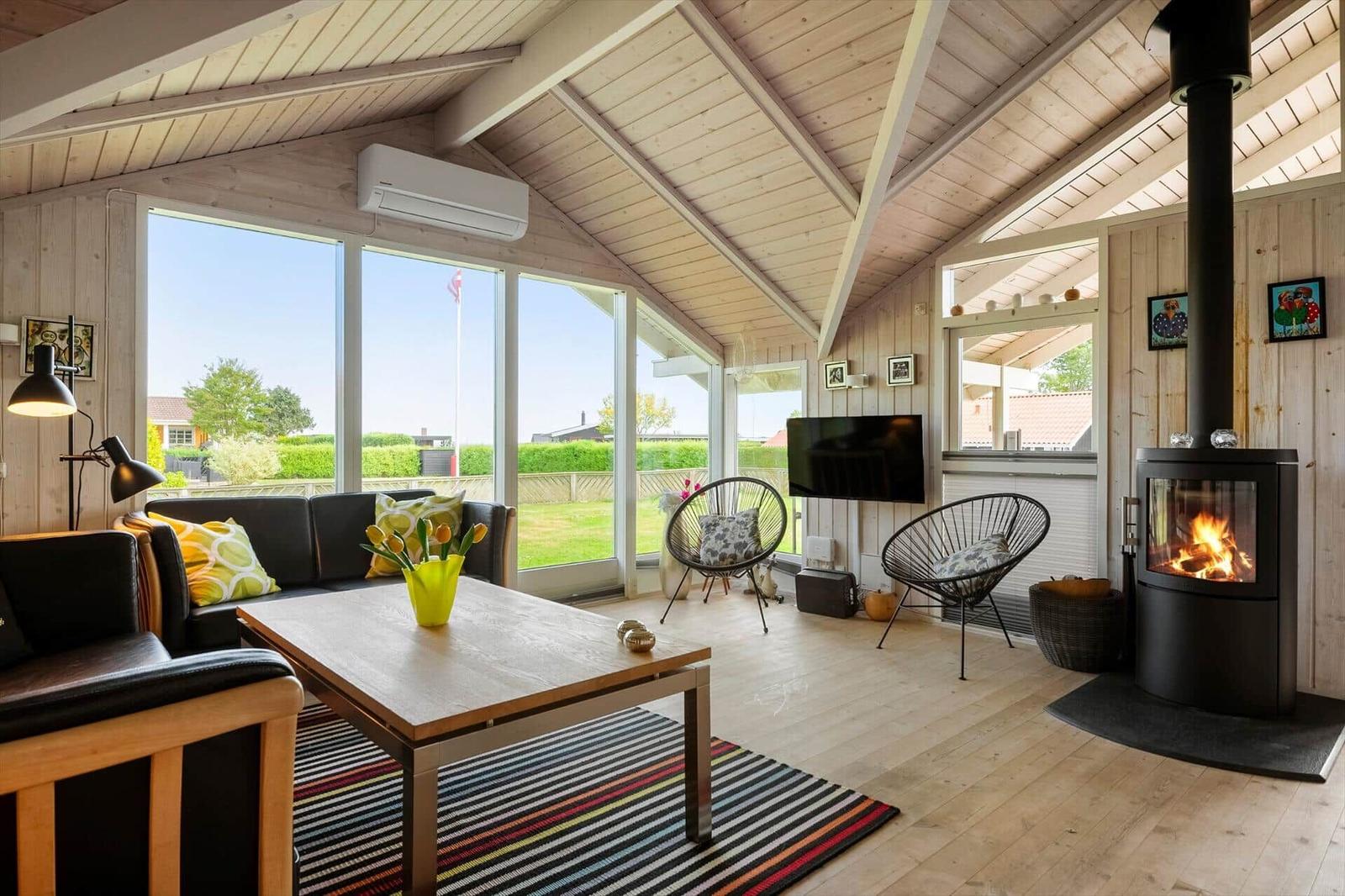 Wohnzimmer mit Kamin, Sofa, Tisch und großen Fenstern zur Aussicht.