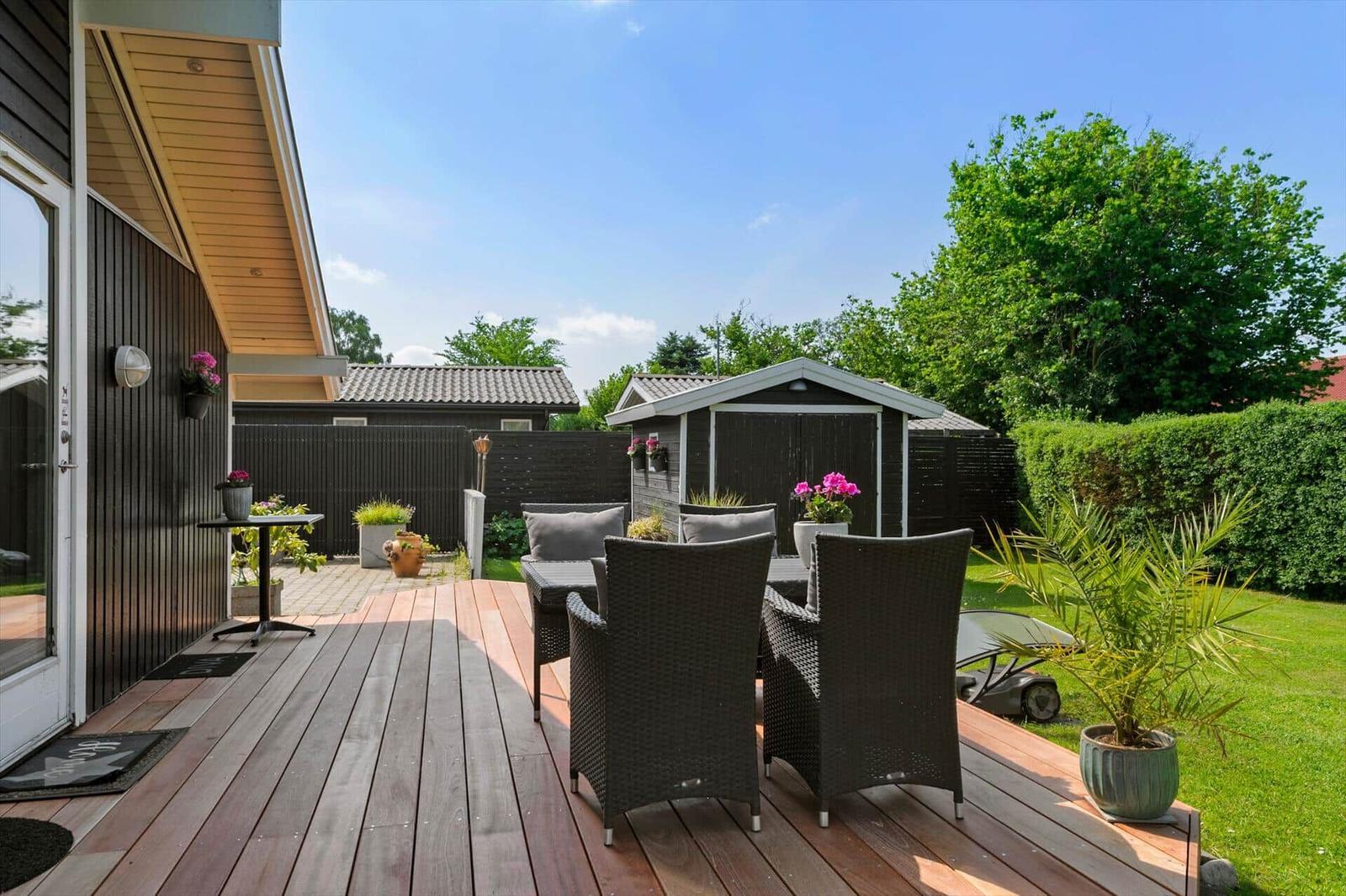 Terrasse mit Gartenmöbeln, Pflanzen und Blick auf den Rasen.