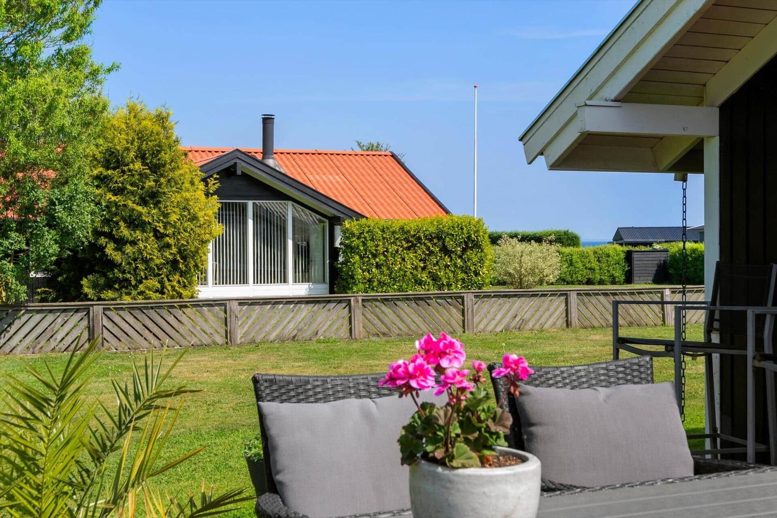 Terrasse mit Sitzgelegenheit und Blumen. Blick auf Garten und Nachbarhaus.