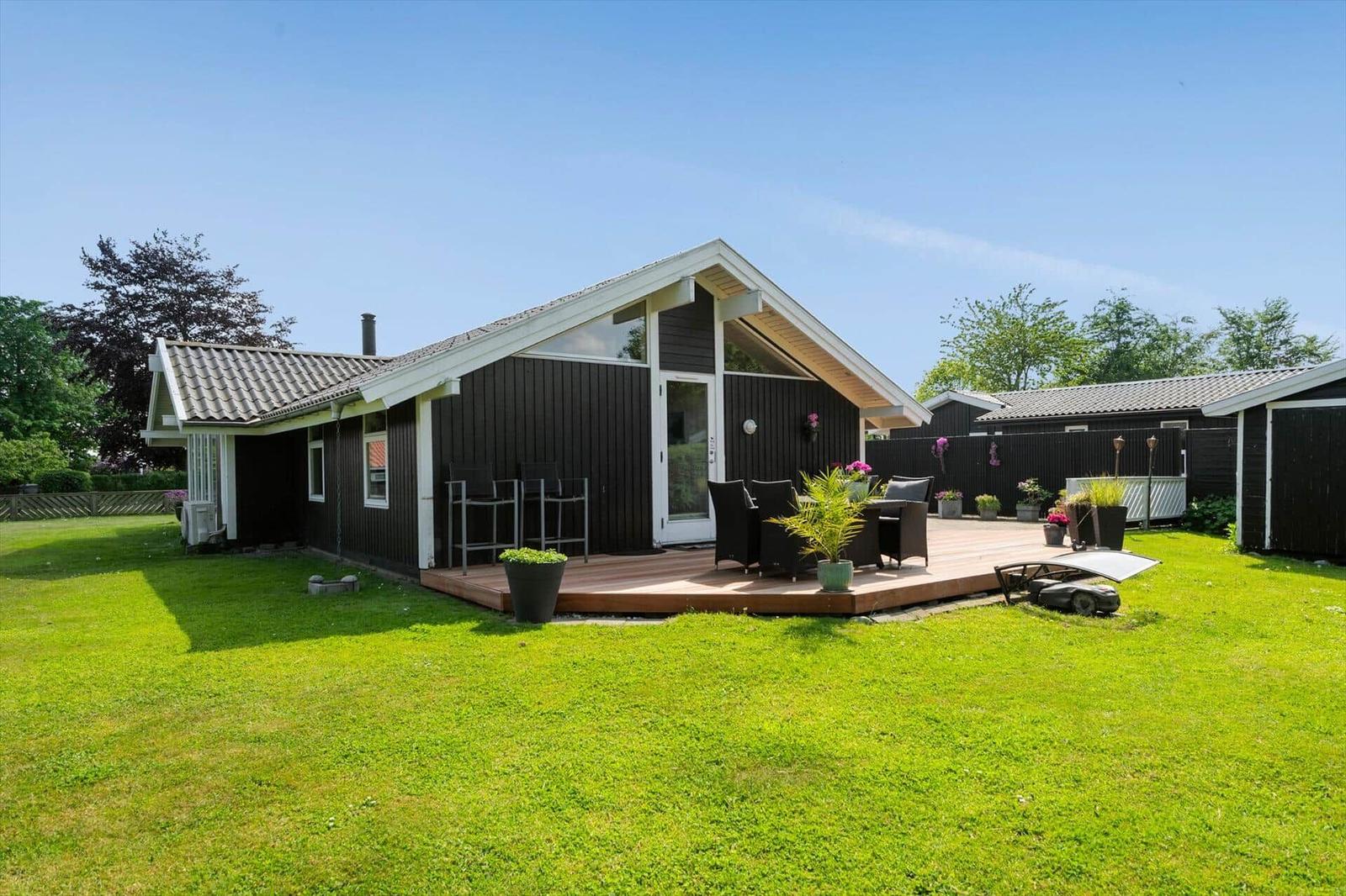 Haus mit Terrasse, Garten und Sitzgelegenheiten im Freien.