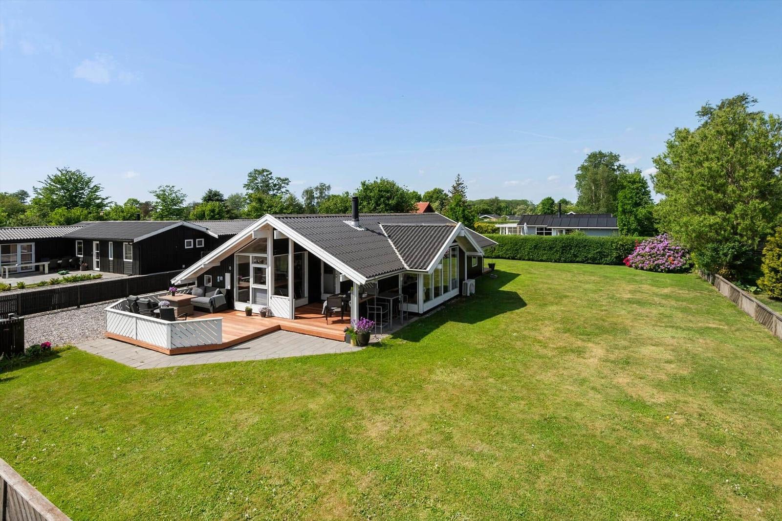 Moderne Villa mit großem Garten und Terrasse. Blick auf umliegende Häuser und Bäume.