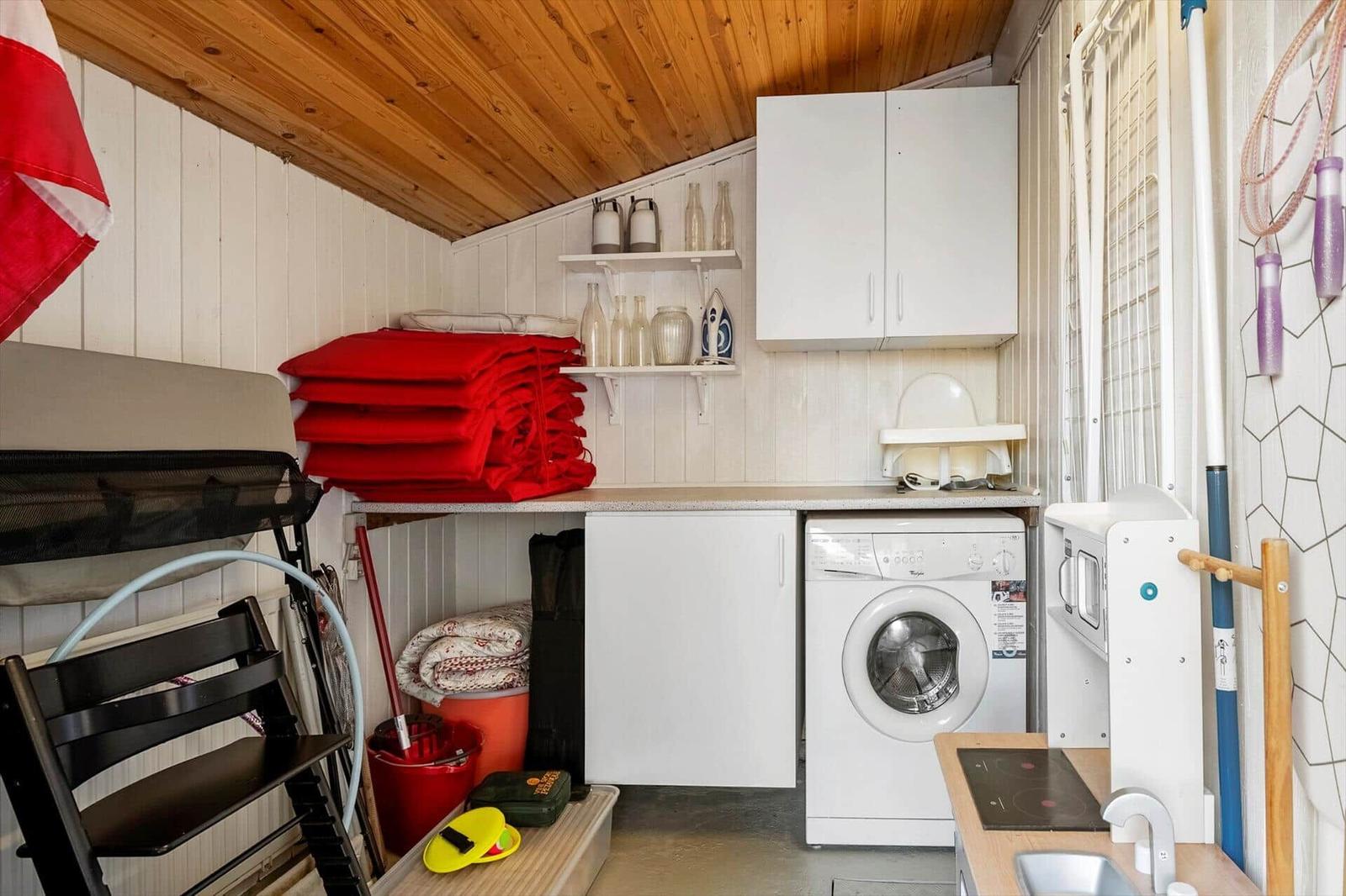 Living space with washing machine, kitchenette, and storage.