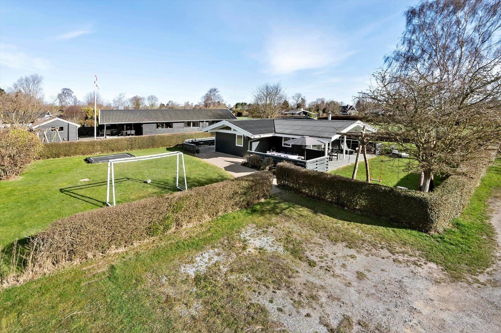 Modern house with large garden, soccer goal, and playground.