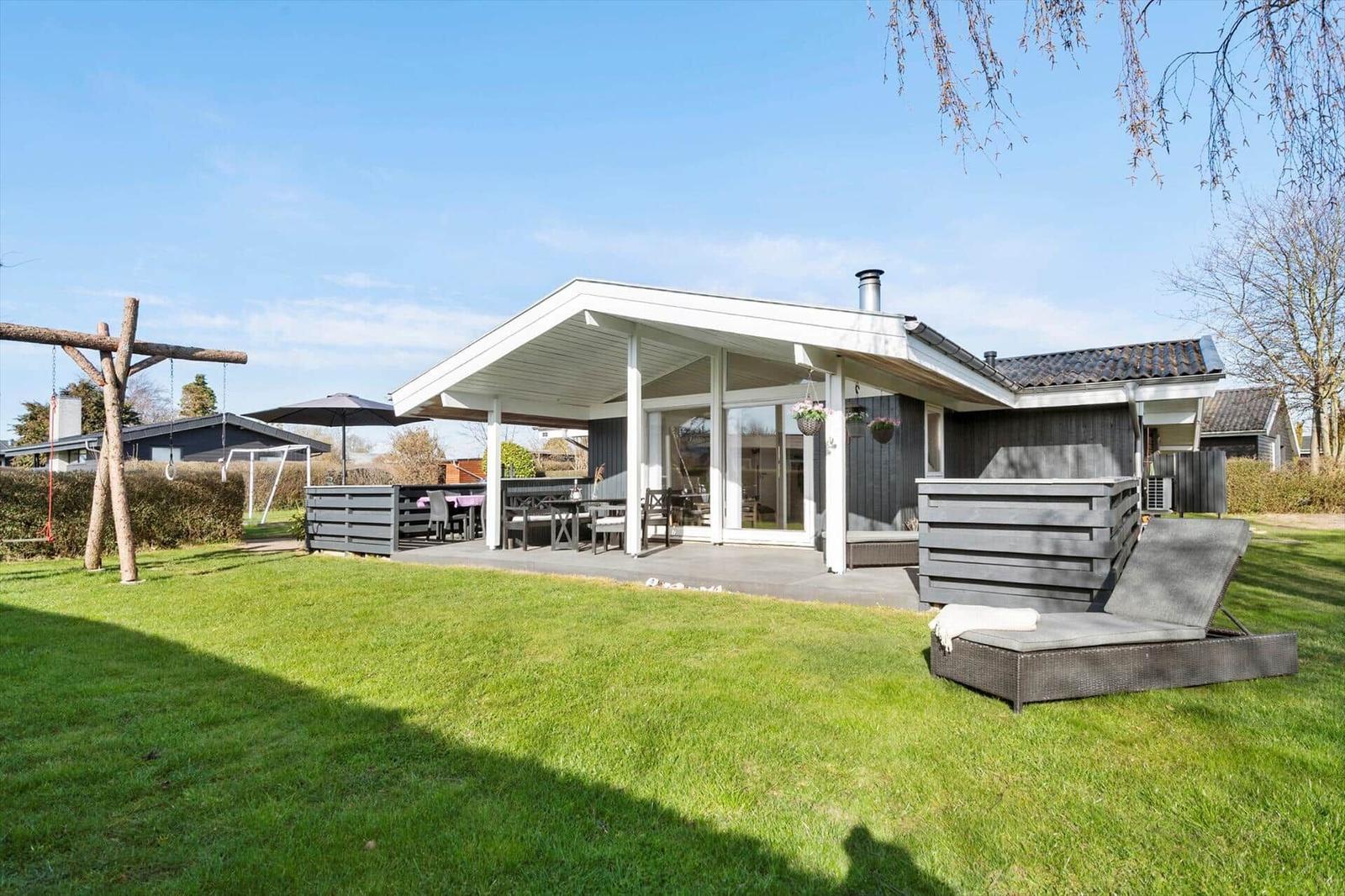 Modern villa with large garden, terrace, and lounge chair. Playground and grilling area.