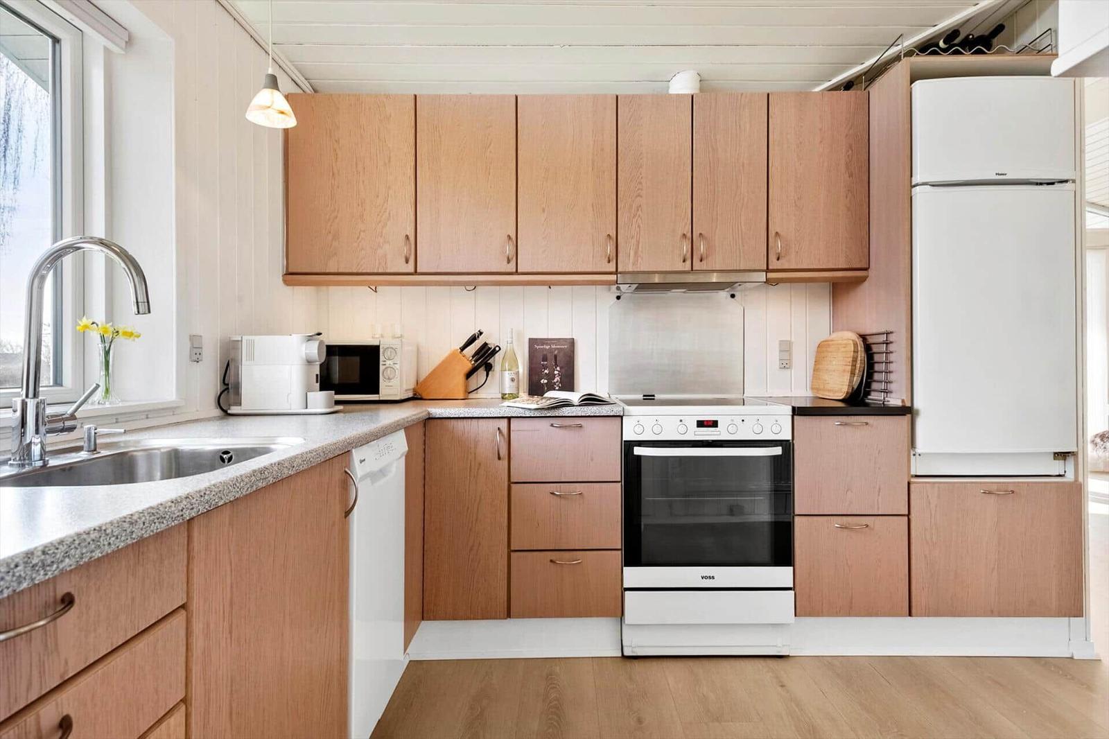 Kitchen with wooden cabinets, sink, stove, and refrigerator.