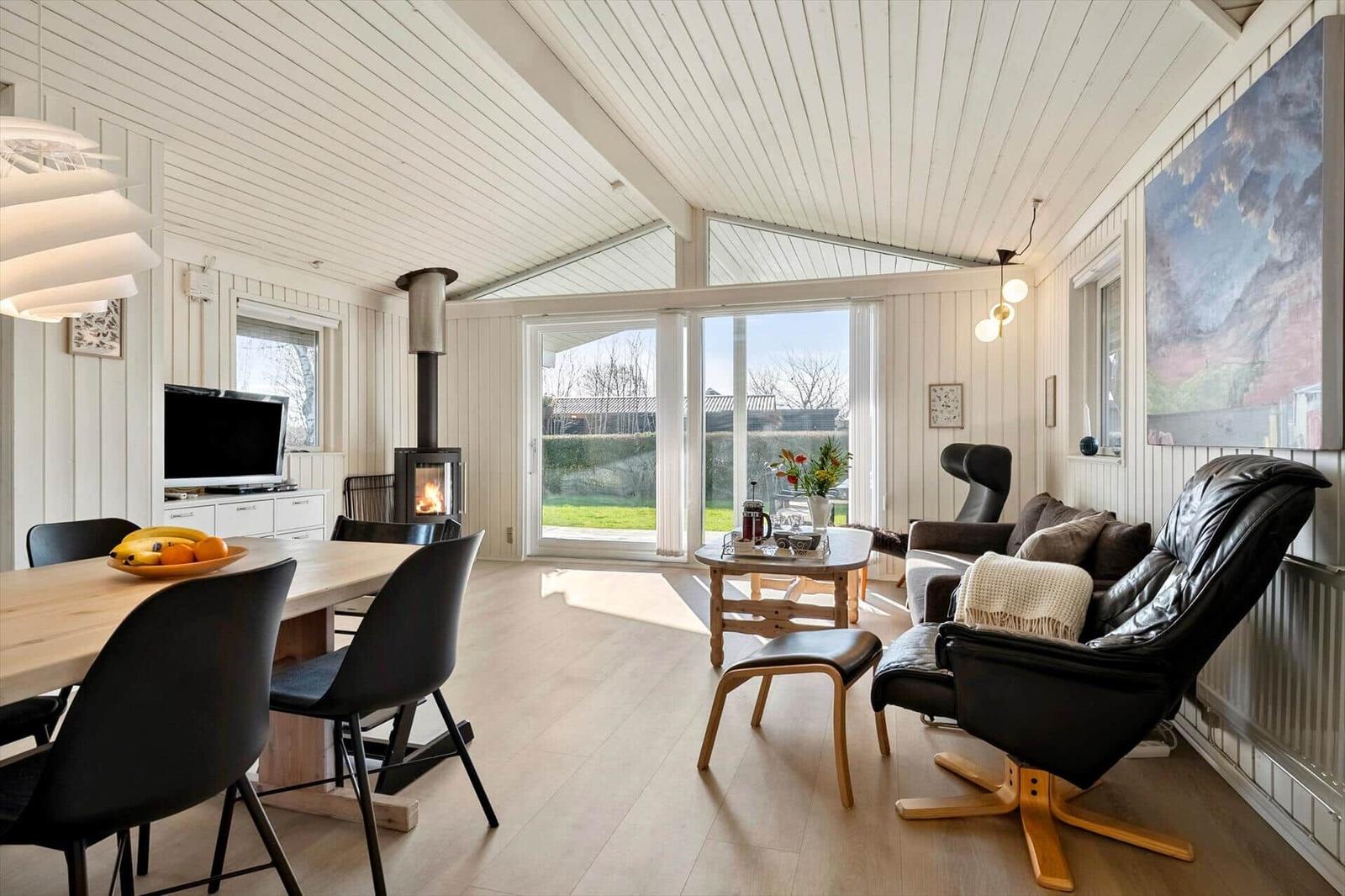 Living and dining area with fireplace, large windows, and black chairs.