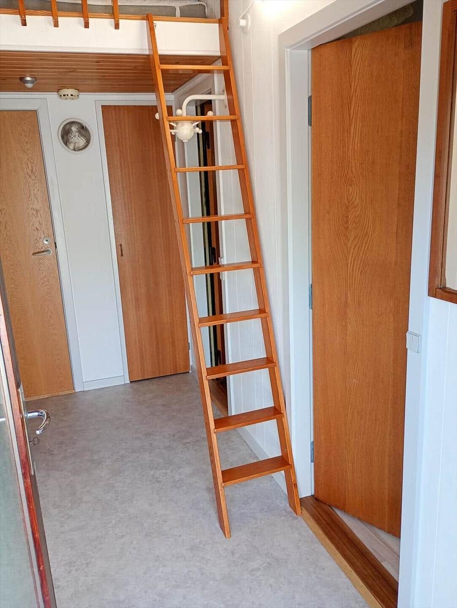 Holztreppe führt zu einer oberen Ebene. Holzwände und Türen. Fliesenboden.