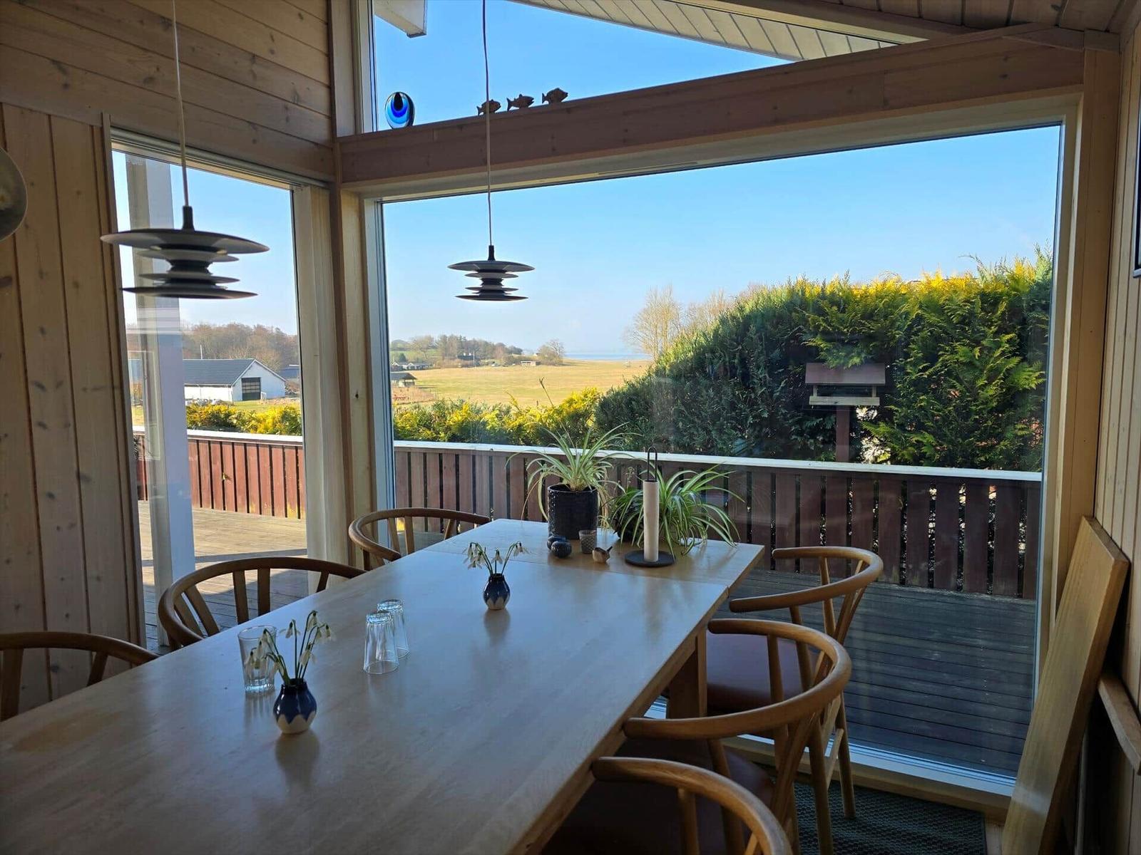 Esszimmer mit Holztisch, Stühlen und Blick auf Garten und Feld.