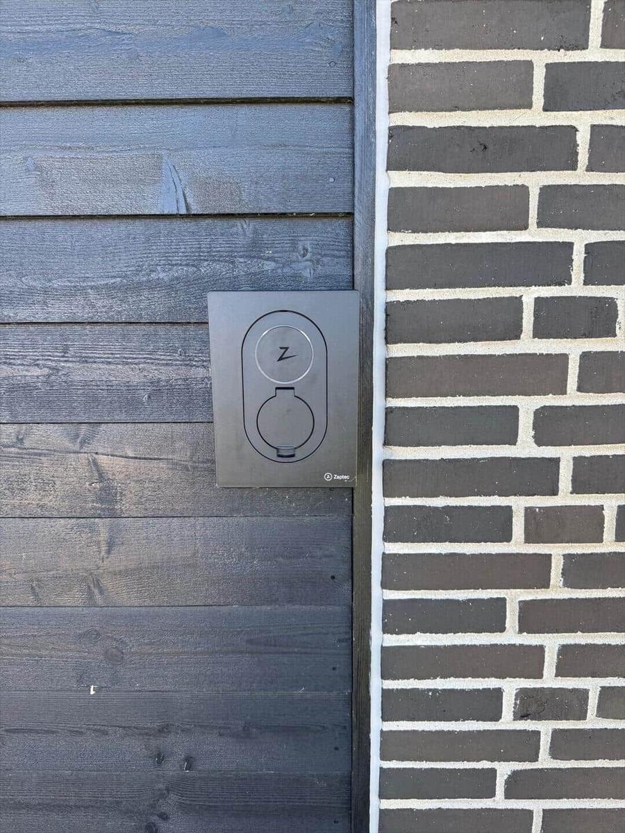 Elektrischer Ladeanschluss an Holzwand und Ziegelwand