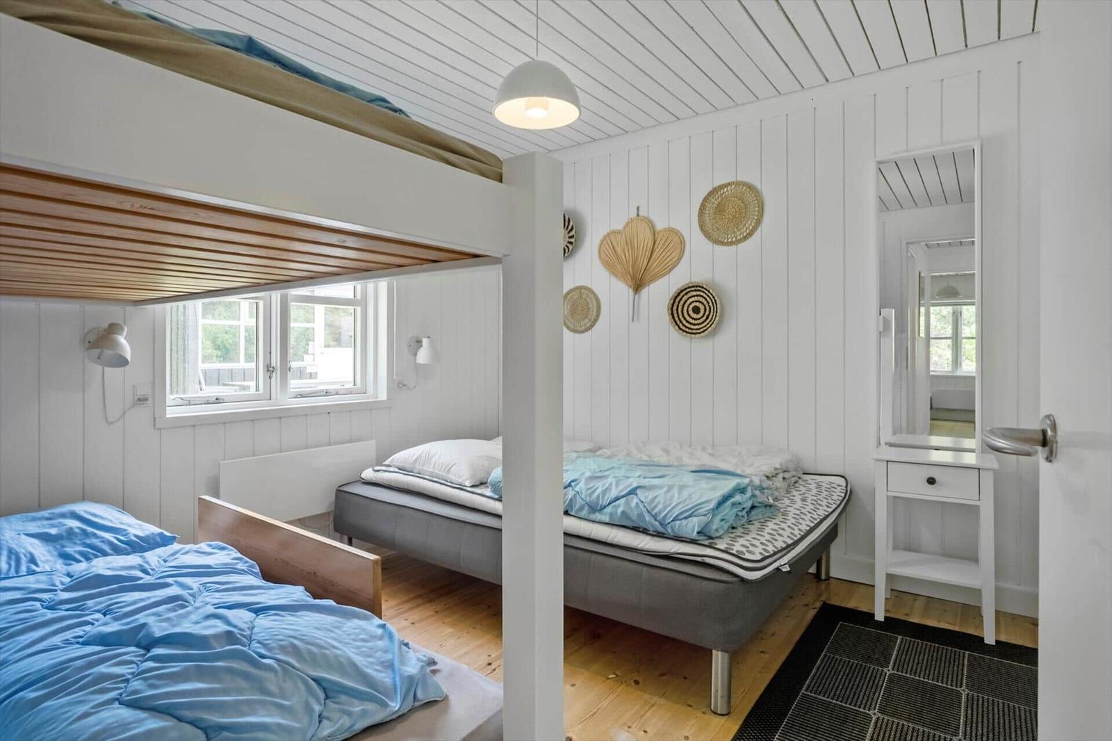 Zimmer mit Hochbett, Matratze und Spiegel. Holzdecke und Wandverkleidung.
