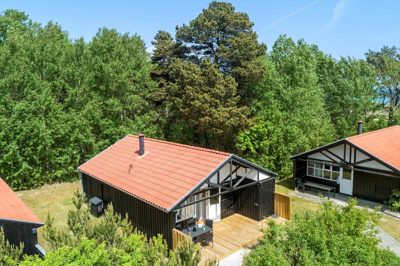 Holzhäuser mit rotem Dach und Terrasse im Grünen