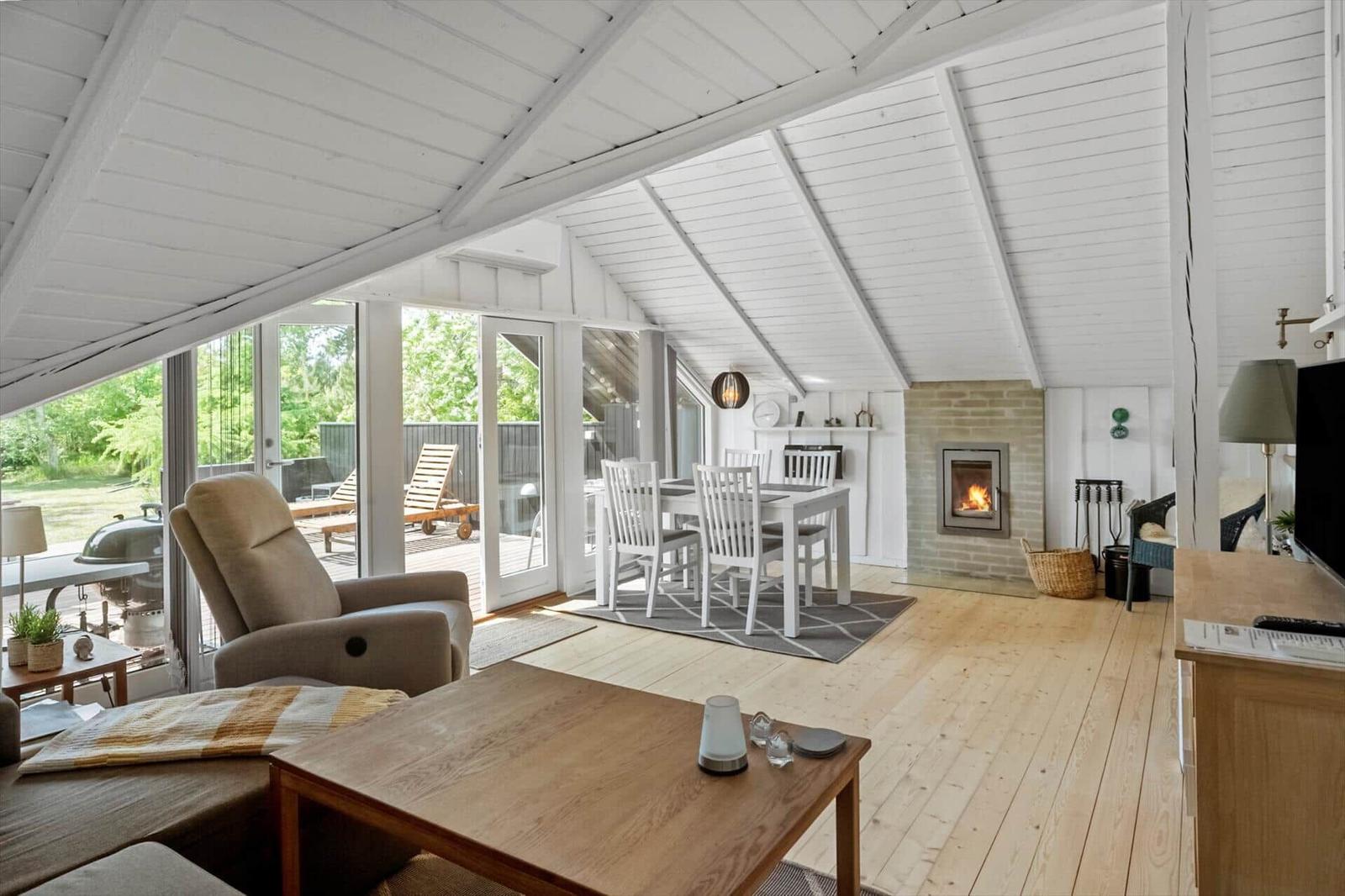Living area with dining table, fireplace, and terrace with garden furniture.