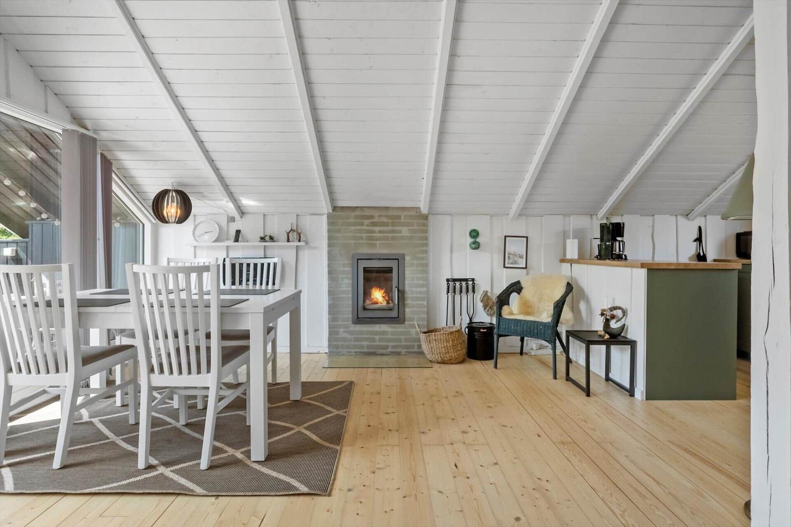 Living and dining area with wooden floor, fireplace, and white furniture.