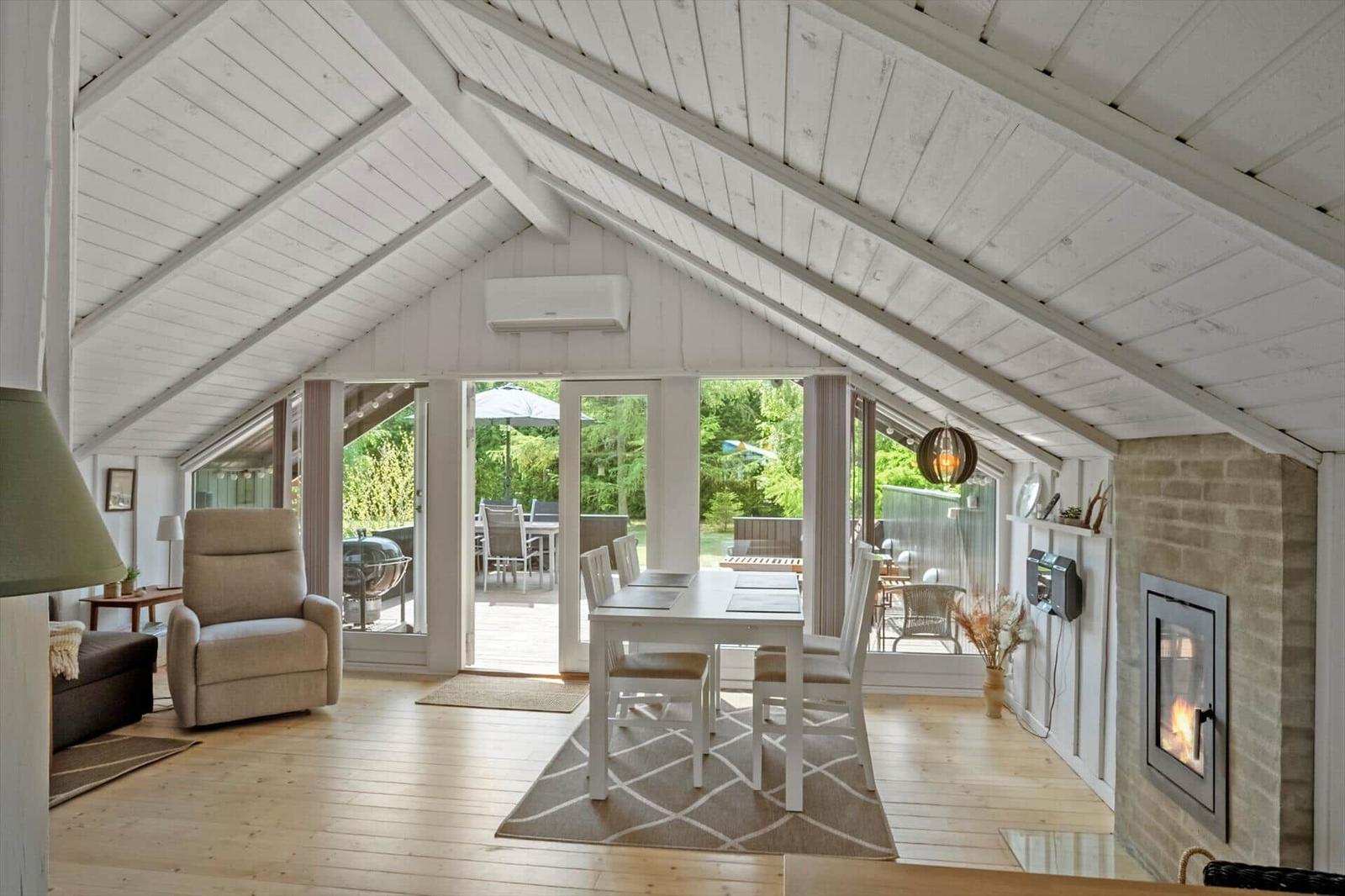 House with dining area, fireplace, and terrace. Wooden floor and white wooden ceiling beams.