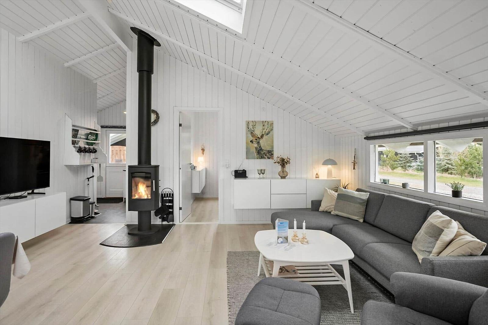 Wohnraum mit Kamin, Sofa und Fenster zur Außenansicht.