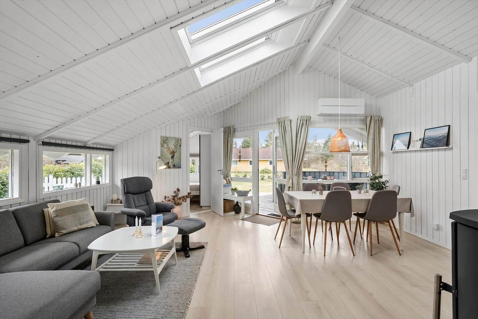 Wohn- und Essbereich mit Sofa, Esstisch und Dachfenster. Holzboden und weiße Wände.