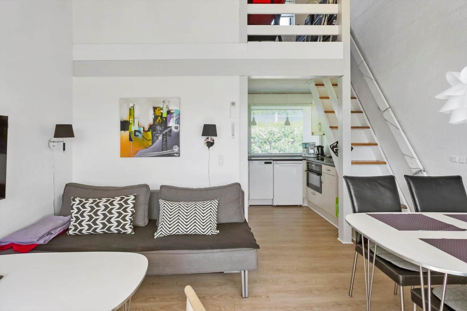 Wohnbereich mit Sofa, Essbereich und Küche unter Dachschräge.