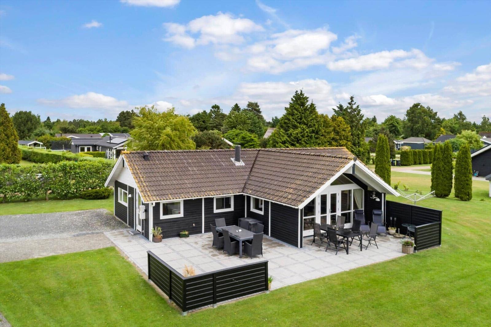Schwarzes Ferienhaus mit Terrasse und Garten. Holzterrasse mit Sitzgelegenheiten.