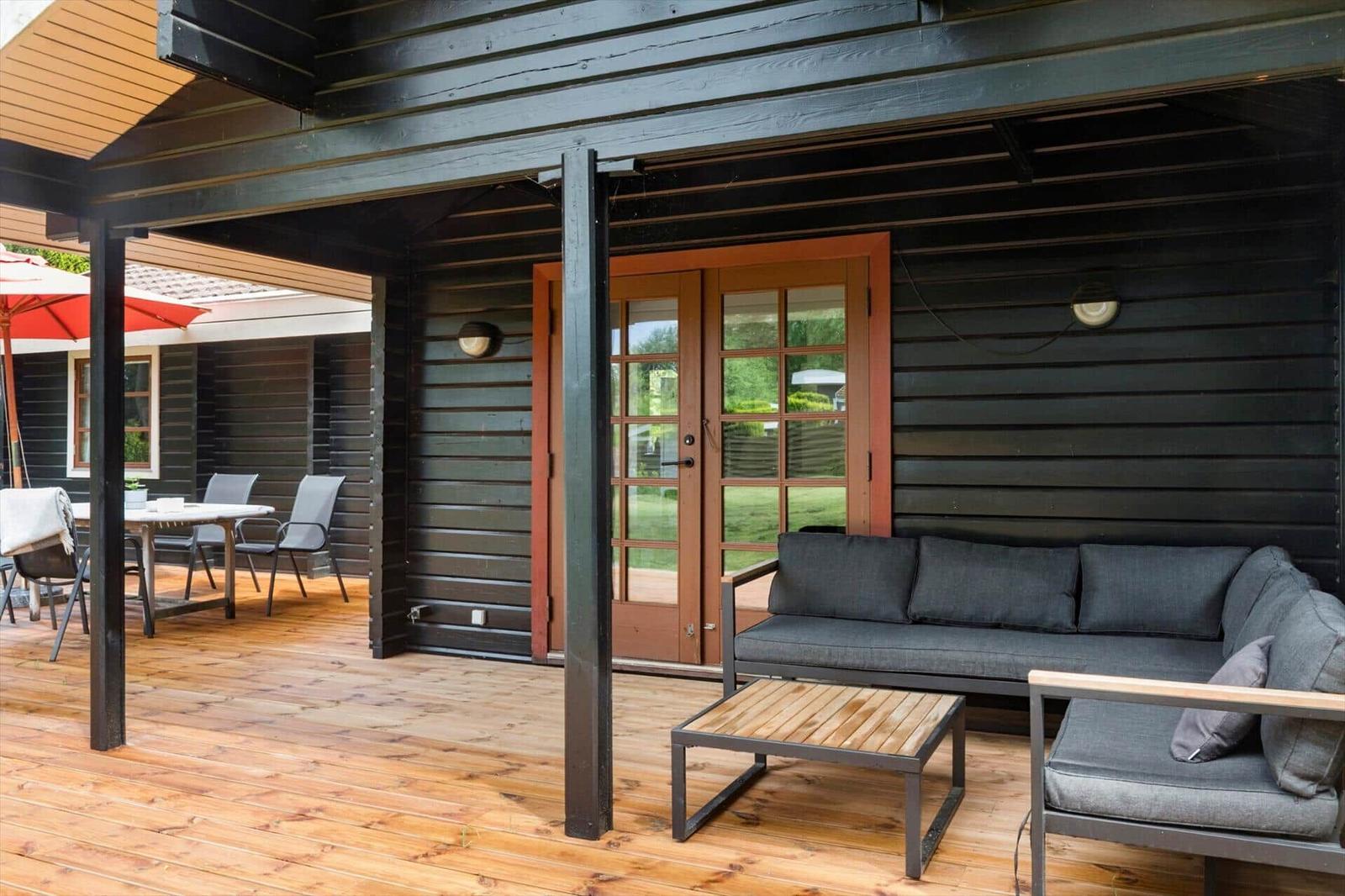 Terrasse mit Sofa, Tisch und Sitzgelegenheiten unter Dach