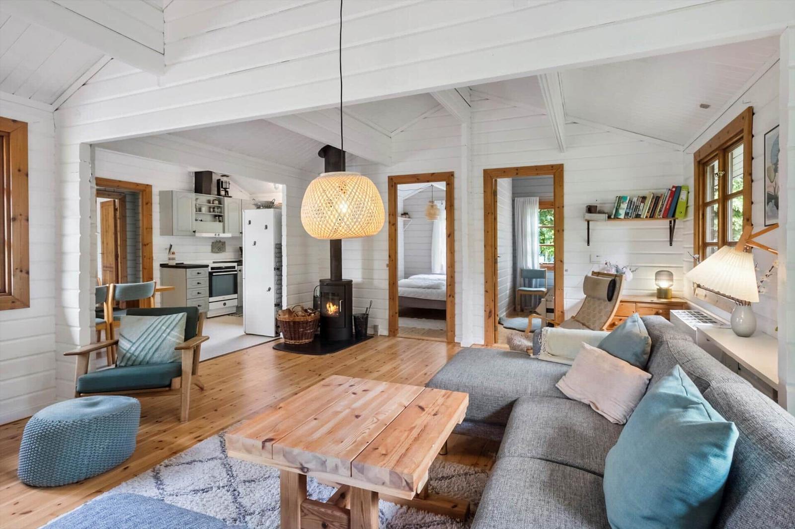 Wohnzimmer mit Kamin, Sofa und Küchenbereich im Hintergrund.