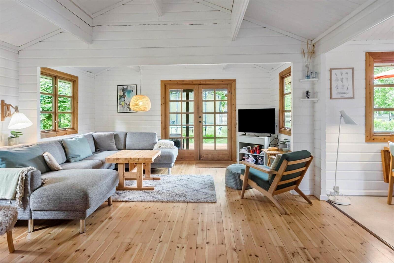 Wohnzimmer mit Sofa, Holztisch und Fernseher. Holzfußboden und weiße Wände.