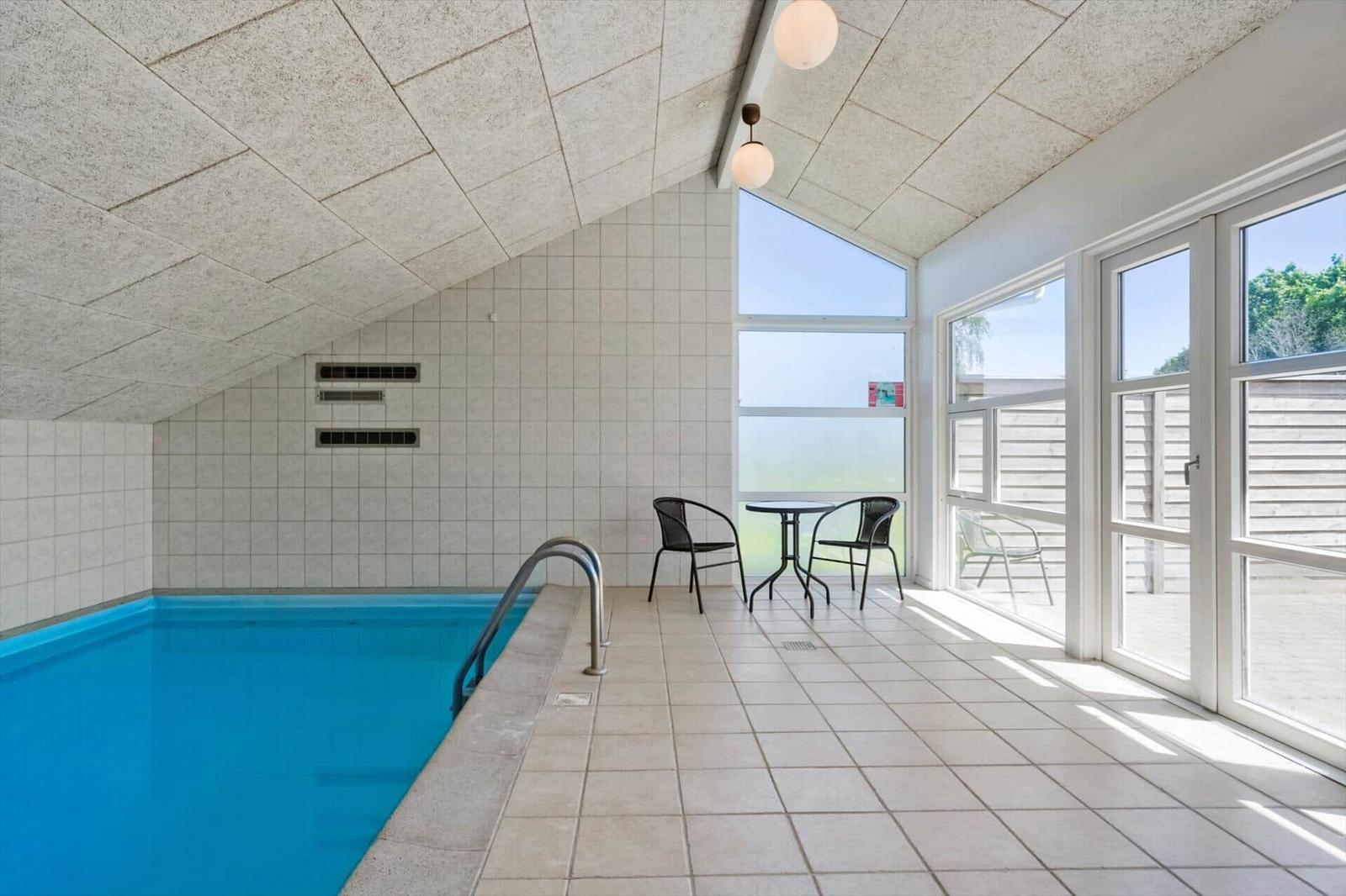 Innenpool mit Sitzbereich und Glasfront zur Terrasse.