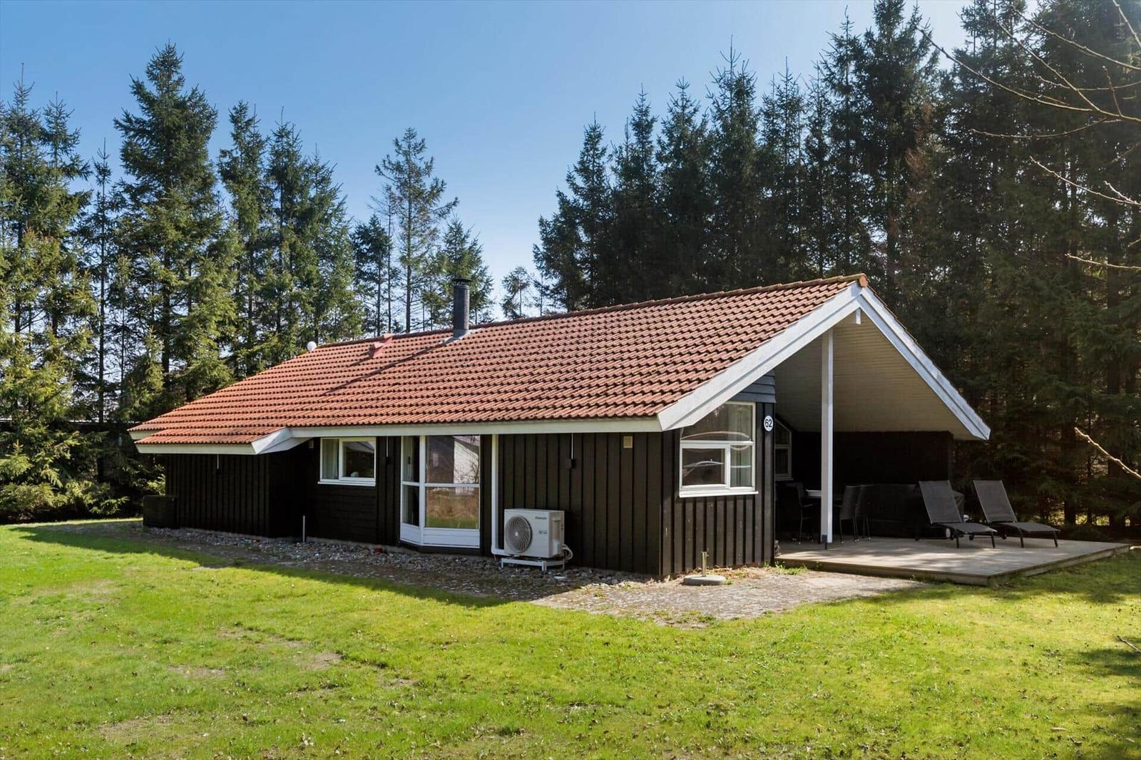 Holzhütte mit Terrasse, Garten und Wald im Hintergrund.