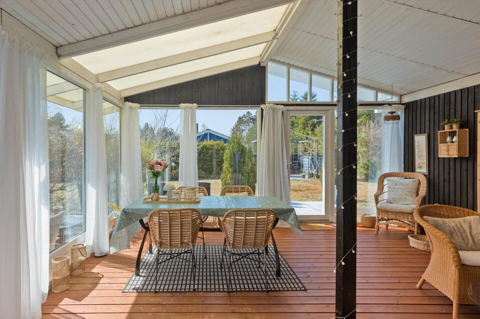 Terrasse mit Esstisch, Stühlen und Sitzgelegenheiten. Durchgehend großzügige Fensterfront.