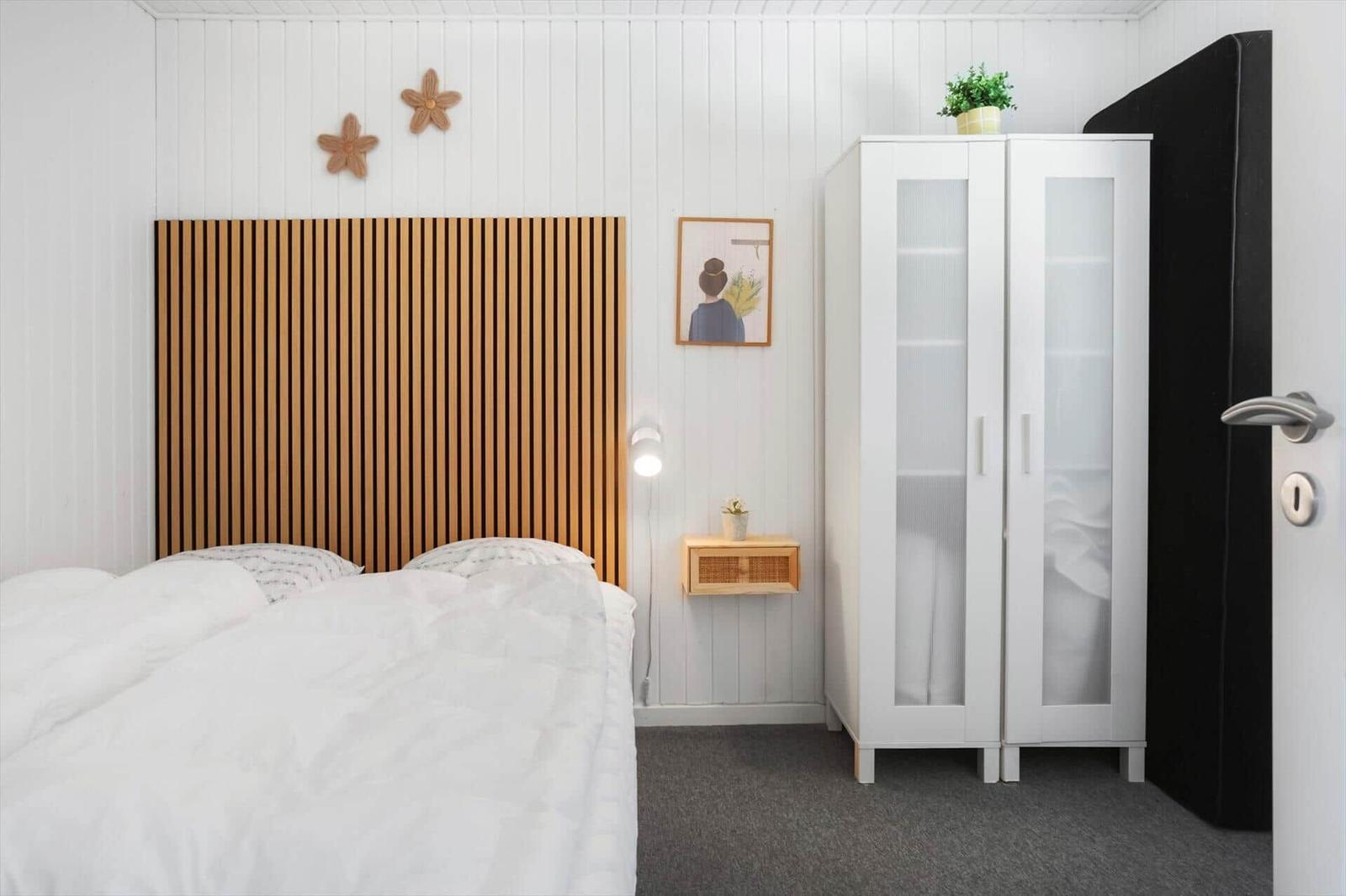 Schlafzimmer mit Bett, Kleiderschrank und Wanddekoration.