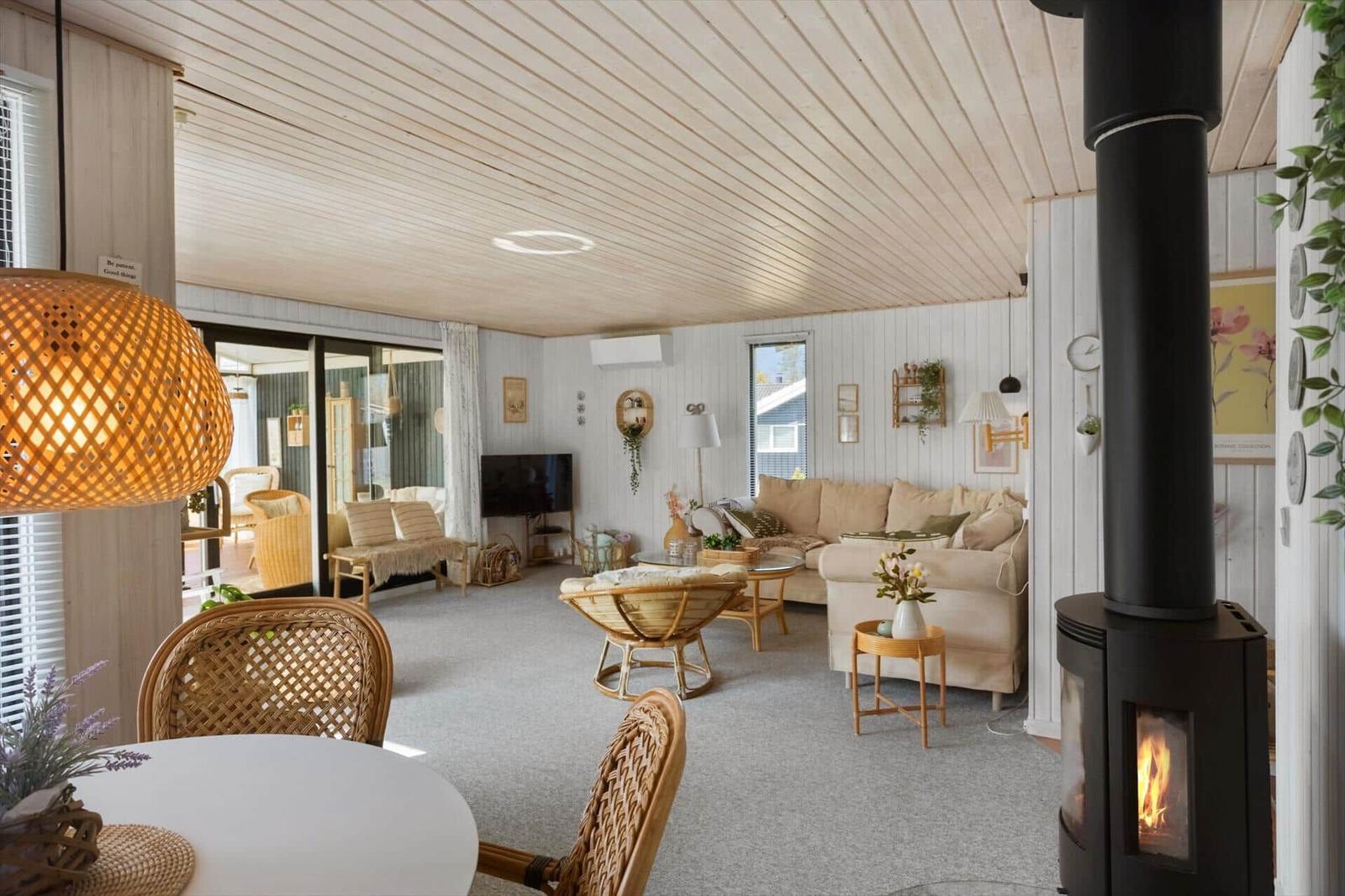 Wohnraum mit Sofa, Kamin und Esstisch. Holzdecke und weiße Wände.
