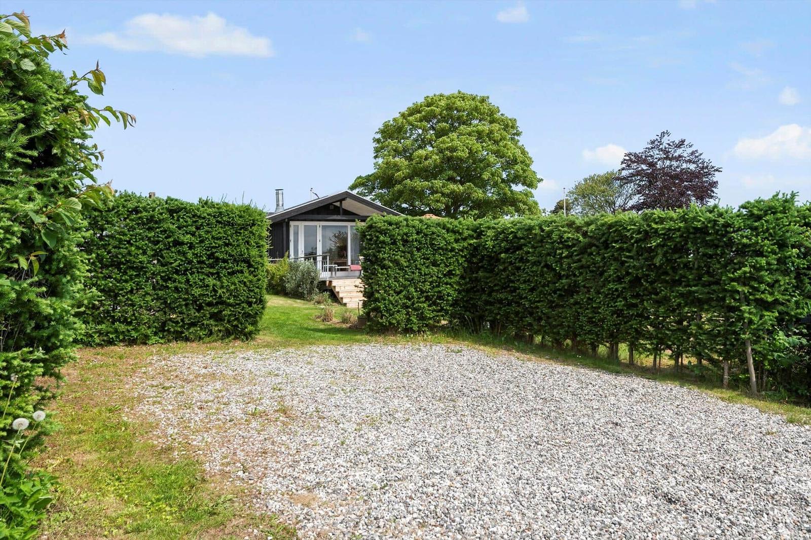 Haus mit Grashügeln und Hecke im Hintergrund. Blick auf die Terrasse mit Stufen.
